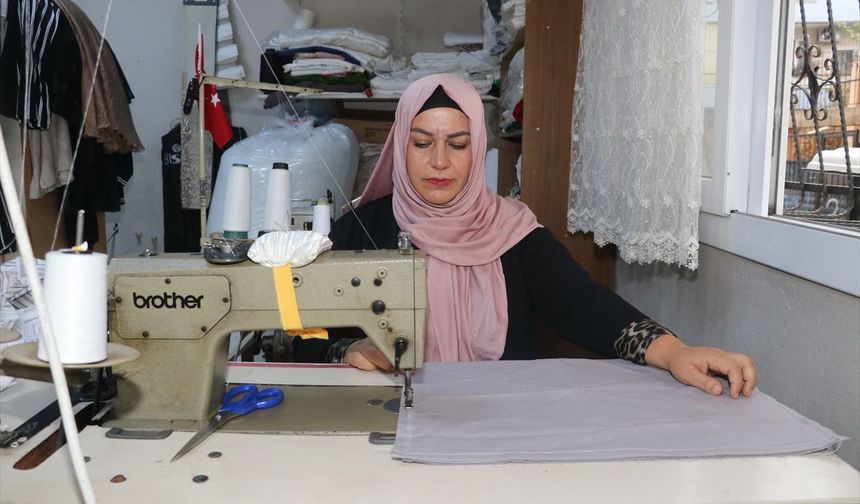 Kadın muhtar mahallelinin hem derdini dinliyor hem terziliğini yapıyor